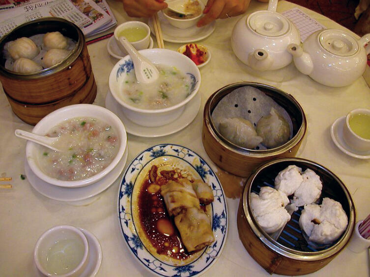 Типичный «дим сам»-завтрак в Гонконге. Слева направо и сверху вниз: креветочные шарики (ха гау), жасминовый чай, курица с овощами, рисовый суп (две чашки с ложками), приготовленная на пару лапша (слева), рисовая лапша с соевым соусом (на тарелке), подогретые на пару булочки со свининой