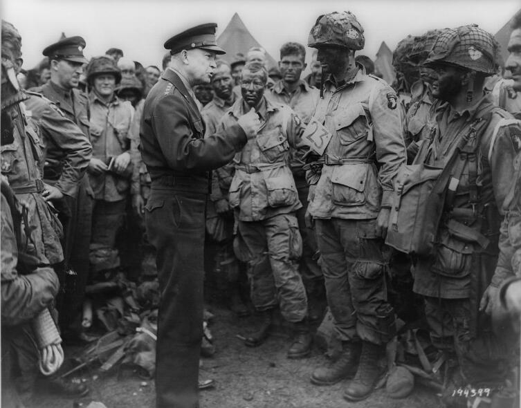 Верховный Главнокомандующий союзными войсками в Европе генерал Эйзенхауэр ведёт беседу с десантниками роты «Е» 502-го парашютно-десантного полка[en] перед началом воздушно-десантной операции в Нормандии. 5 июня 1944 г.